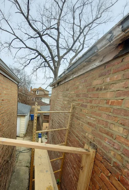 After: Brick parapet: damaged section, then the rebuild in progress.
